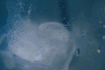 Blurred photo, water droplets clinging to the side of a glass with ice inside.