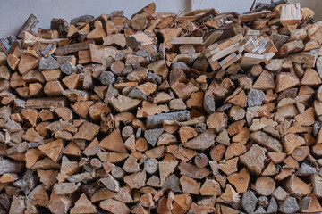 A large pile of sawn wood is stacked against the wall to light the stove. Energy security of private households.