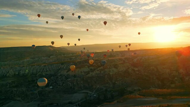 Summertime adventure. Rising sun illuminating beautiful sky full of hot-air balloons flying over the town of Cappadocia, Turkey. High quality 4k footage