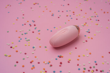 Pink sex toy vibrator on a pastel pink background with confetti - obrazy, fototapety, plakaty