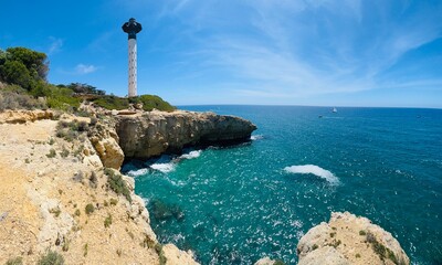 Coastal lighthouse on rocky cliff overlooking turquoise sea © ZEDRAY