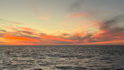 Obraz premium Sunset over the open sea with dramatic sky and horizon