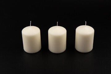 White candles on dark background. Close-up, copy space.