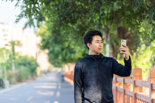 Asian sportsman is using mobile phone outdoors.