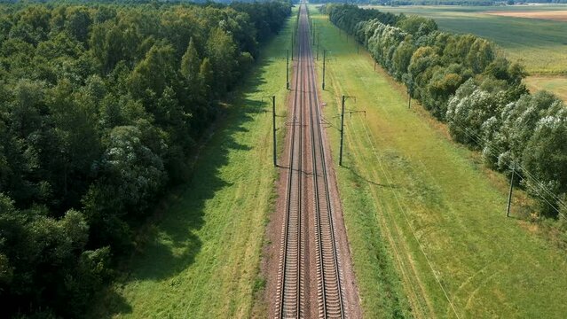 Aerial flying forward on empty straight intercity railway road to horizon. Transportation and delivery of goods. Public rail transport for passengers. Flying at speed over parallel rails and sleepers
