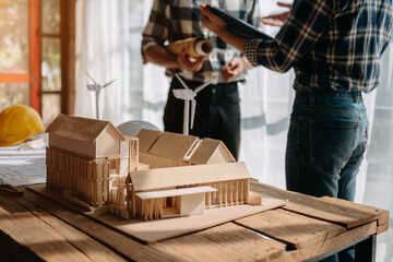 Scale model house on table with architects. Two architects making architectural model in office together. to form a new buildin