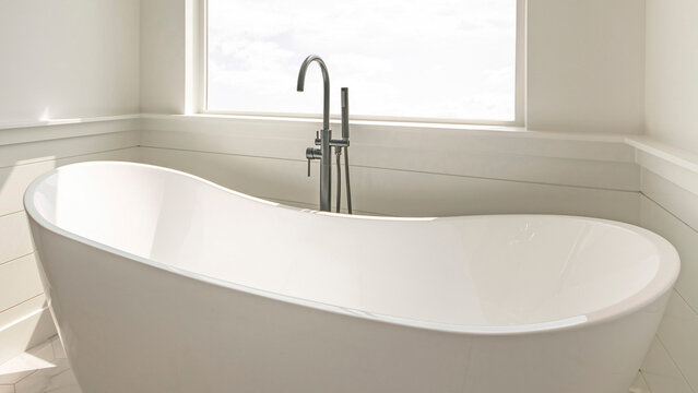 Panorama Modern solid base freestanding tub with floor mount dual faucets against the square picture window