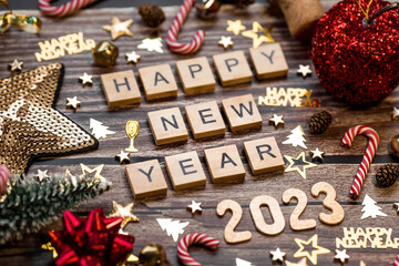 Banner. The symbol of the number 2023 with gold and red balls, stars, sequins and a Christmas tree on a wooden background. The concept of celebrating a Happy New Year 2023 and Christmas.