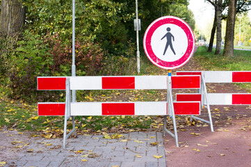 Road closed with barriers and sign for pedestrians for roadworks.