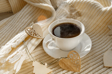 Details of a still life in the living room of a home interior. A white cup of coffee and a scarf by the frozen window. Cozy autumn winter concept.