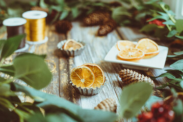 Slices of dried orange and festive decorative foliage and pinecones on a table