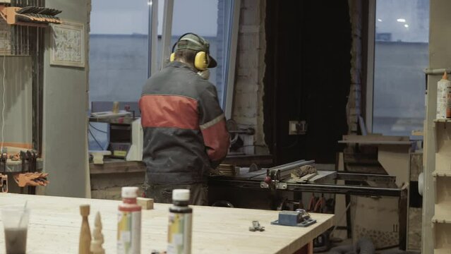 the carpenter makes the processing of wood blanks in the workshop. working process of woodworking with tools and automatic machines. 4k. small particles of chips and dust fly to the sides. woodworkin