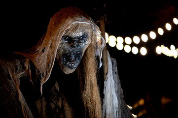 Witch with a broom and a monster face on a dark halloween horror night, bokeh light background