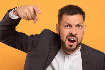Aggressive man pointing on orange background. hate concept