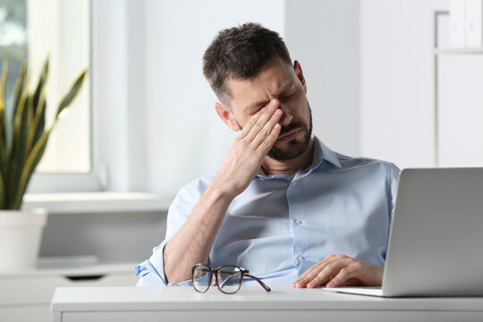 Man suffering from eyestrain at desk in office