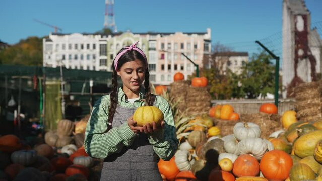 Female farmer holding pumpkin on the background of autumn harvest.