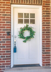 Vertical White door exterior with glass panel above the wreath and lockbox