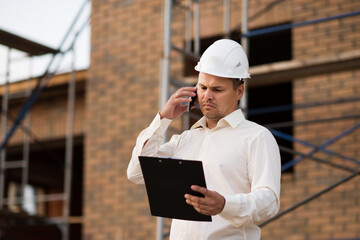 The engineer discusses the plans for the construction of the object on the phone, the architect reviews and controls the construction of the house