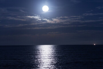 満月が夜の海に光の道をつくる