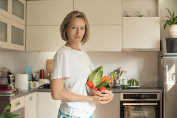 young positive smiling woman with vegetables in the kitchen