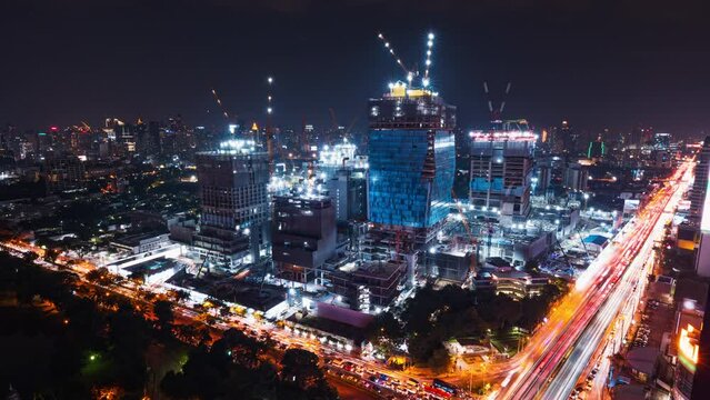 Time-lapse of construction site at night, car traffic transportation on road in Asia city, high angle view. Advanced building technology, busy downtown cityscape, developing industrial country concept