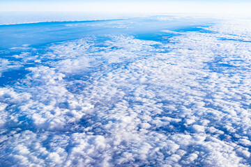 Naklejka na ściany i meble The sky from the plane window. Clouds below against the blue sky