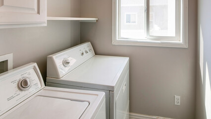 Panorama Laundry room interior with light gray wall and white cabinets and laundry units