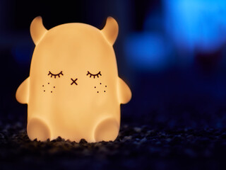 Child night lamp of cute ghost daemon sleeping iluminated on warm color and cold color on background