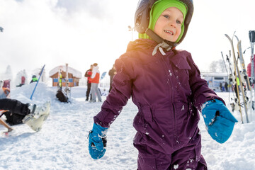 Cute adorable little kid boy enjoy having fun sledging down hill of snow heap snowdrift at alpine...