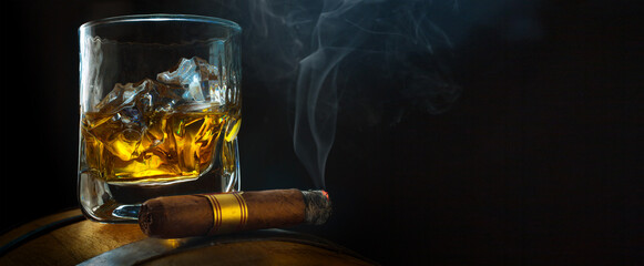 a glass of whiskey with ice on a oak barrel, a steaming cuban cigar  in a smoky atmosphere of a night bar. Men's club banner idea. Copy space for text