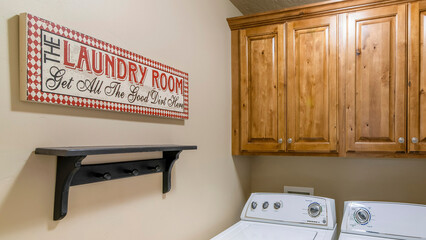 Panorama Small laundry room interior with shelf and decorative statement signboard on the wall