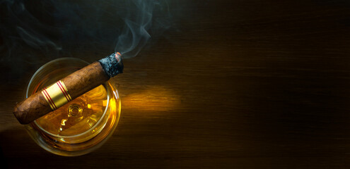 a glass of brandy on a wooden table, a steaming cuban cigar in a smoky atmosphere of a night bar