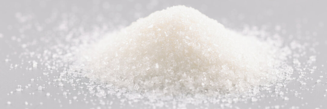Sugar crystals pile on grey background, heap of sweet powder, sugar substitute