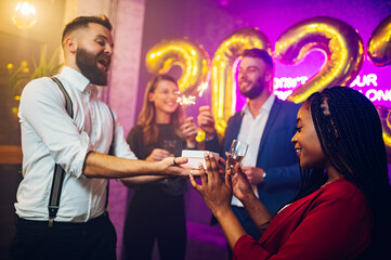 Multiracial couple exchanging gifts for birthday party or new years eve