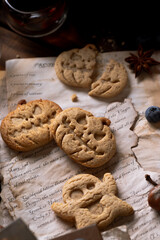 Cookies in the shape of pumpkins and ghosts are in a plate on the table. Next to a teapot and mugs, an autumn still life