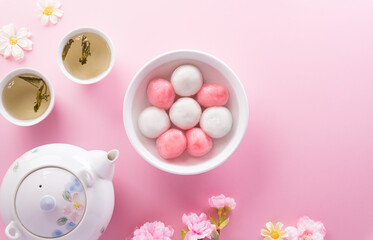 Tang Yuan(sweet dumplings balls), a traditional cuisine for Mid-autumn, Dongzhi (winter solstice ) and Chinese new year with plum flower and tea on pastel background.