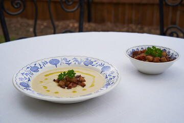 Creamy celery root soup and bread crumbs served in rustic deep plate and bowl outside in the garden restaurant. Traditional healty and full of nutrition food, typical example of the czech cuisine.