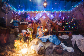 Christmas crib at a Cologne Christmas market. The scene where the Virgin Mary gave birth to Jesus and he lies in the cradle surrounded by people who have come to celebrate the Nativity of Christ - obrazy, fototapety, plakaty