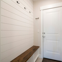 Square Mudroom interior with white door to the garage and wood panel interior