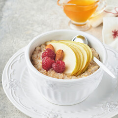 Oatmeal. Bowl of oatmeal porridge with raspberry, pear and honey on gray concrete old table background. Hot and healthy food for Breakfast, top view, flat lay