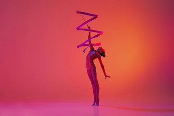 Poster Young flexible teen girl rhythmic gymnast in motion, action isolated over pink background in neon light. Sport, beauty, competition, flexibility, active lifestyle © master1305