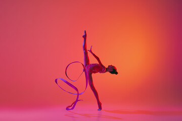 Young flexible teen girl rhythmic gymnast in motion, action isolated over pink background in neon light. Sport, beauty, competition, flexibility, active lifestyle