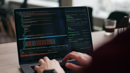 Close up of freelancer's hands typing code on laptop keyboard. Camera slides around developer's figers writing program code on computer display. Programmer working on online application database. - Powered by Adobe