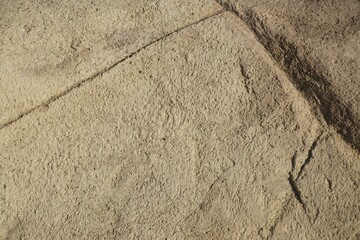 Braungraue Sandsteinfläche mit Muster und Riss bei Sonne am Mittag im Herbst