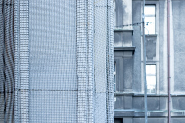 Facade protection net placed on the building's column. Old, vintage building in the background.