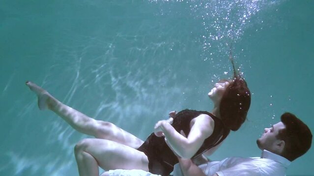 A woman and a guy are swimming underwater. A woman kisses a guy underwater.