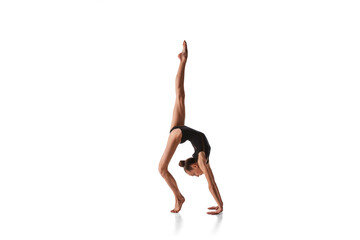 Balance. Portrait of junior gymnast in black sport swimsuit doing gymnastics excercises isolated...