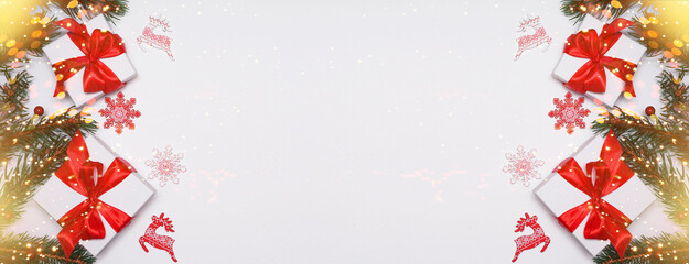   Spruce, fir branches, red berries, gift box on red background. Frame border. Christmas New Year composition background. Christmas lights. Space for text.