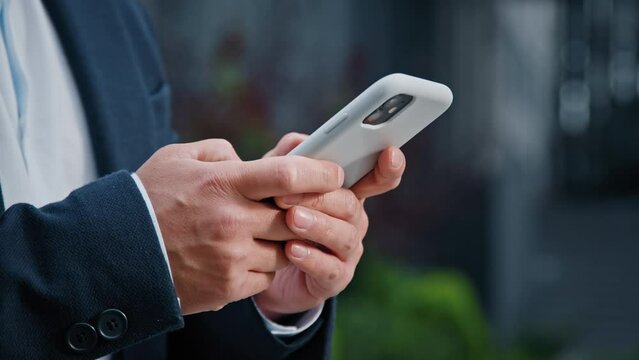 Close up male hands typing texting browsing mobile phone. Unrecognizable unknown man businessman in formal suit working with smartphone in city outdoors manager managing project remote with telephone