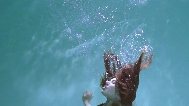 A pregnant girl swims and dives under the water. Medical training for a pregnant woman with a big belly will dive underwater. Woman learning to give birth in water.